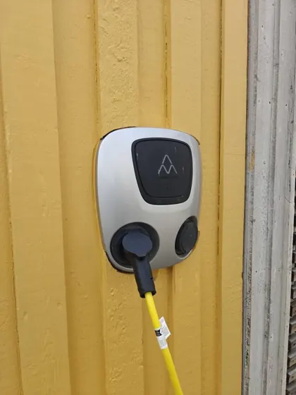 Charge Amps-laddbox monterad på gul träfasad i Halmstad